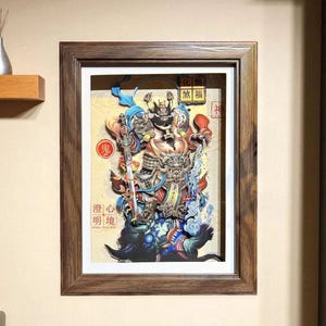 May include: Framed artwork featuring a detailed, multi-layered illustration of a deity with a sword, in vibrant colors. The artwork includes Chinese characters and is set in a dark wood frame, mounted on a beige wall.