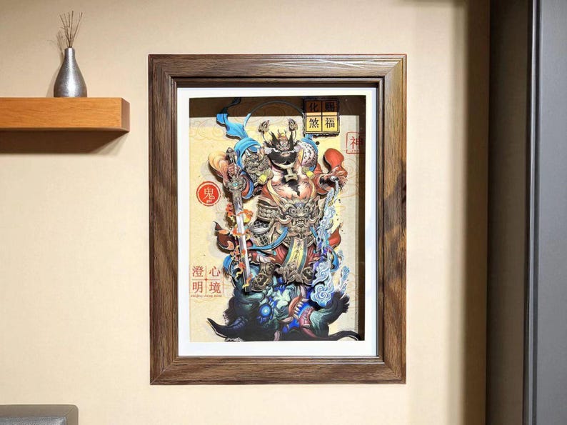 May include: Framed artwork featuring a detailed, multi-layered illustration of a deity with a sword, in vibrant colors. The artwork includes Chinese characters and is set in a dark wood frame, mounted on a beige wall.