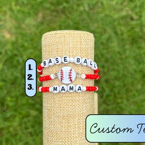 May include: Three baseball-themed bracelets. The top bracelet spells "BASEBALL" with white letter beads and red accents. The middle bracelet features a baseball charm. The bottom bracelet spells "MAMA".