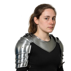 May include: Silver-colored metal shoulder armor with articulated plates. The armor is worn over a black shirt. The design includes a neck guard and straps for secure fastening. This medieval-style armor is suitable for cosplay or historical reenactments.