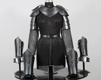 Peut inclure: Un ensemble complet d'armure médiévale noire, comprenant une chemise en cotte de mailles, des protège-épaules, des protège-bras et des protège-jambes. L'armure est exposée sur un mannequin, mettant en valeur son design et son savoir-faire.