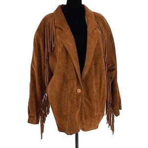 May include: A brown suede jacket with fringe detailing on the sleeves and shoulders. The jacket has a single button closure and a classic lapel collar. The garment is displayed on a black mannequin.