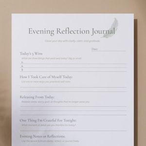 May include: A white Evening Reflection Journal with text and prompts for daily reflection. The journal includes sections for wins, self-care, releasing thoughts, gratitude, and notes. A feather graphic is in the upper right corner. The journal is designed to promote clarity, calm, and gratitude.