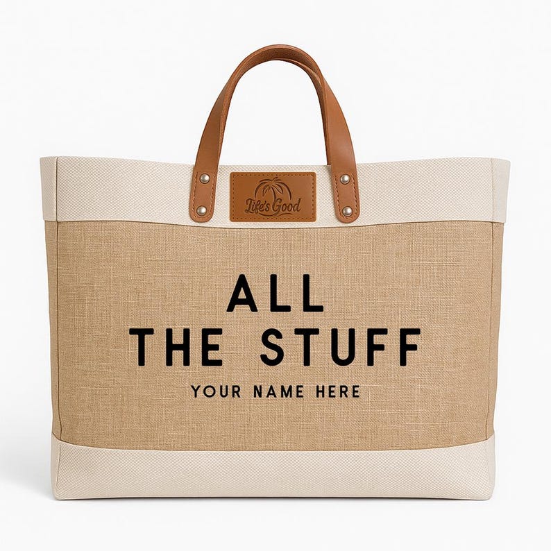 May include: A large tote bag with a tan burlap-like center and off-white top and bottom. The bag has brown leather handles and a leather patch that says "Life's Good". The text "ALL THE STUFF YOUR NAME HERE" is printed on the front.