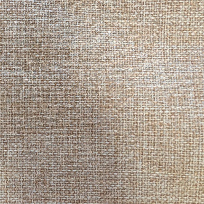 May include: Close-up of a woven fabric with a textured appearance. The fabric is a blend of light and dark beige threads, creating a natural, neutral color palette. The weave is tight and consistent, suggesting a durable material.