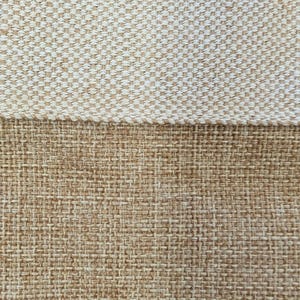 May include: Close-up of a woven fabric with a two-tone design. The top portion is a light beige, tightly woven pattern, while the bottom is a darker, coarser weave in a tan color. The textures create a visual contrast.