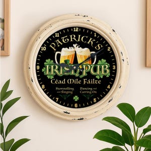 May include: Cream-coloured, round wall clock with black face featuring "Patrick's Irish Pub" text and two beer mugs. The clock has a distressed finish and displays the time with black hands. The text "Céad Mile Fáilte" is also visible.