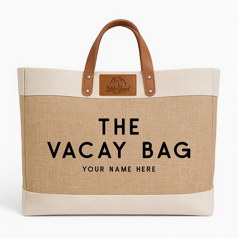 May include: A large beige and cream tote bag with brown leather handles and accents. The bag features the text "THE VACAY BAG" in black, with space for personalization below. A leather patch reads "Life's Good".