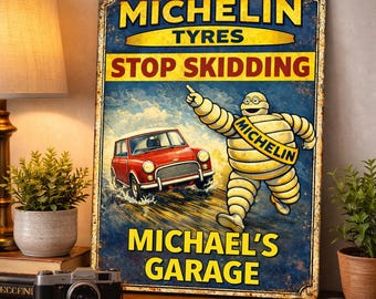 Puede incluir: Cartel metálico vintage con el muñeco Michelin señalando un coche rojo. El texto dice "MICHELIN TYRES STOP SKIDDING" y "MICHAEL'S GARAGE". El cartel tiene un aspecto envejecido con una combinación de colores azul y amarillo.