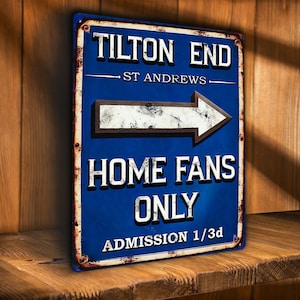 May include: A distressed blue metal sign with white lettering. The sign displays "TILTON END" and "HOME FANS ONLY", with an arrow pointing right. It also includes "ST ANDREWS" and "ADMISSION 1/3d". The sign has a rustic, aged appearance.
