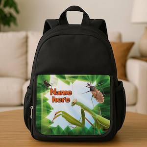 May include: Black backpack featuring a colourful insect graphic with a praying mantis and a brown insect. The graphic includes the text "Name here" in orange. The backpack has a top handle and side pockets.