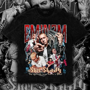 May include: Black t-shirt featuring a graphic of Eminem with the text "Eminem" in red and white. The design includes multiple images of the artist and the words "Slim Shady" and "This opportunity comes once in a lifetime!"