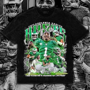 Puede incluir: Camiseta negra con un gráfico de jugadores de los Philadelphia Eagles en verde. El diseño incluye el texto "PHILADELPHIA EAGLES" y "Jalen Hurts" en verde, junto con la cita "I CARRY MY SCARS WITH ME EVERYWHERE I GO. I DON'T FORGET."
