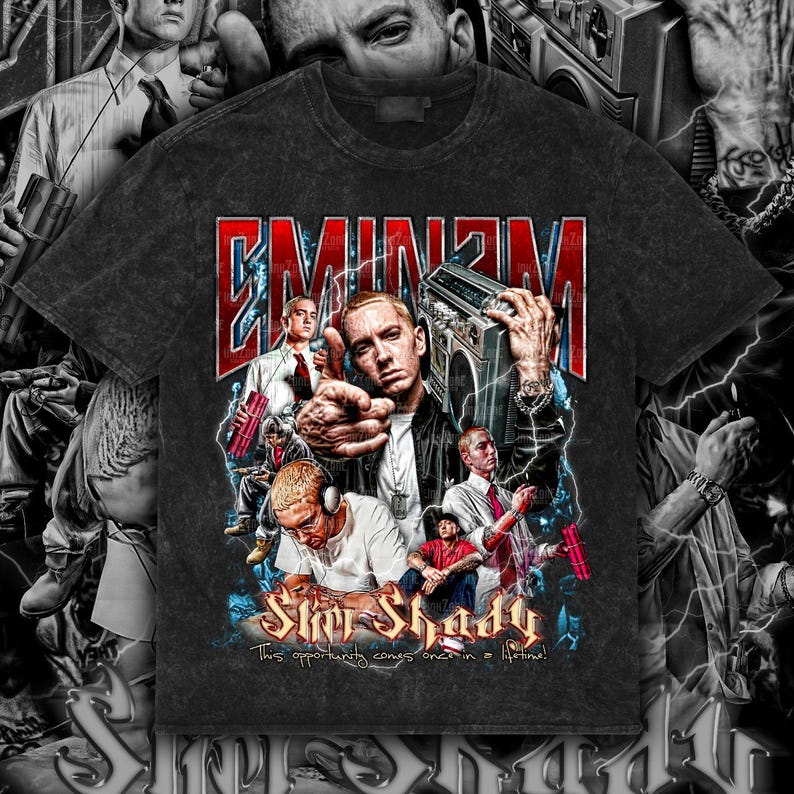 May include: Dark gray t-shirt featuring a graphic of Eminem with the text "EMINEM" in red and white. The graphic includes images of Eminem holding a boombox and other images of the artist. The text "Slim Shady" and "This opportunity comes once in a lifetime!" are also included.