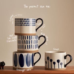 Può includere: Quattro tazze in ceramica con motivi blu scuro dipinti a mano su sfondo crema. Il testo recita: The perfect size for: Coffee, Tea, Hot (OR iced!) Chocolate, Mug cakes, Overnight oats e Soups. Ogni tazza ha un manico di colore blu.