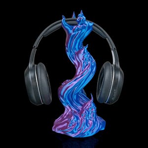 May include: A black pair of headphones rests on a vibrant, swirling headphone stand. The stand is a mix of blue and purple hues, resembling flames. The background is solid black, highlighting the stand and headphones.