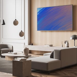 May include: A modern living room with a large flat-screen TV displaying an abstract blue and purple painting. The room features a light-colored sectional sofa, a round coffee table, and a gray armchair. Decorative pendant lights and a floor lamp add to the ambiance.
