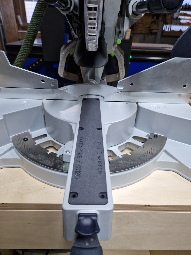 May include: A close-up of a silver miter saw with a black label that reads "KAPEX KS388 / KS120" and "Z-Saw Clearance 0.6".