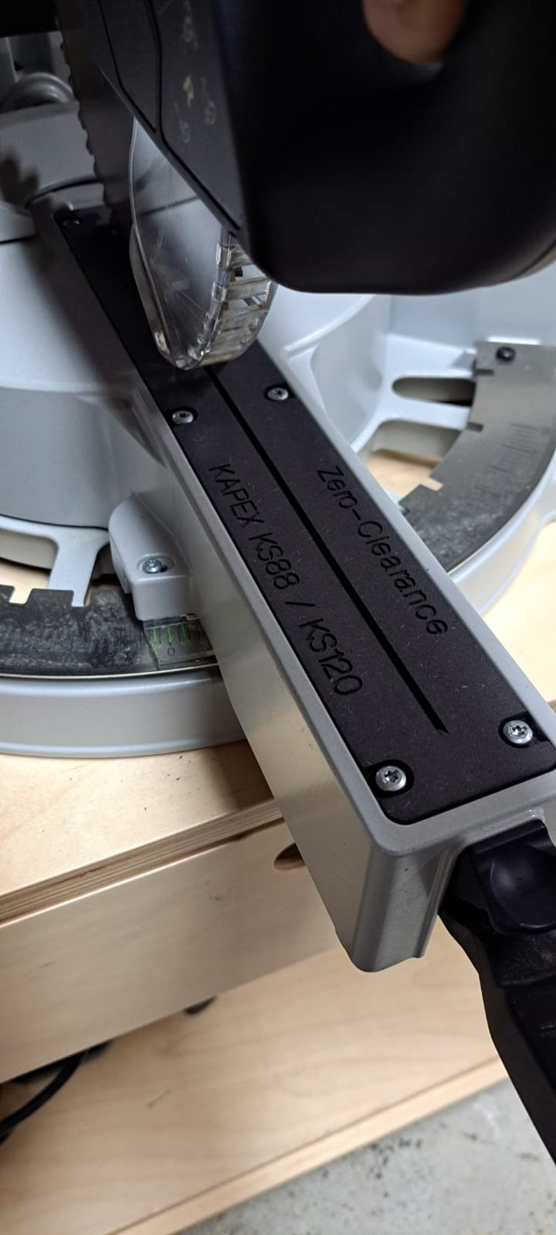 May include: A close-up of a gray and black saw blade guard with the text "Zero-Clearance" and "KAPEX KS88 / KS120" printed on it.