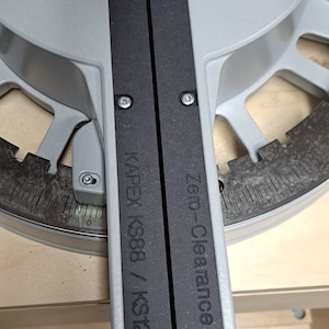 May include: Close-up of a silver and black saw with the text "Zero-Clearance" and "KAPEX KS88 / KS120" printed on it.