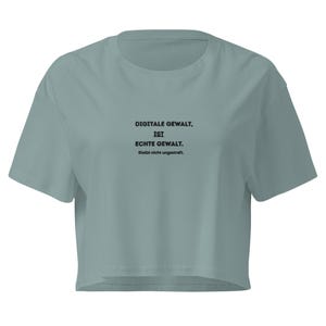 Könnte beinhalten: Ein hellblaues, kurzes T-Shirt mit kurzen Ärmeln. Auf dem Shirt steht in schwarzer Schrift: "DIGITALE GEWALT, IST, ECHTE GEWALT. Bleibt nicht ungestraft."