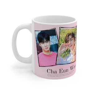 May include: White ceramic mug featuring two framed photos of a person. The mug has a light pink background with the text "Cha Eun Woo" and a warning message. The mug has a white handle.