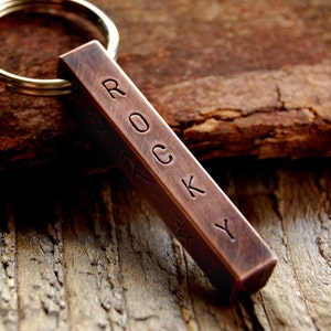 May include: A copper bar keychain with the name "ROCKY" engraved on it.
