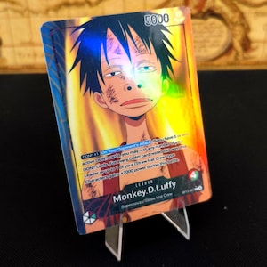Könnte beinhalten: Eine holografische Sammelkarte mit Monkey D. Luffy von den Supernovas/Strohhut-Crew. Die Karte hat eine Stärke von 5000 und enthält Spieltext. Die Figur ist mit schwarzen Haaren und einem roten Hemd dargestellt.