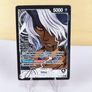 May include: A trading card featuring a character with white hair and dark skin, with red eyes. The card has a black background with white and silver accents. Text includes "5000 ?", "Imu", and game instructions.