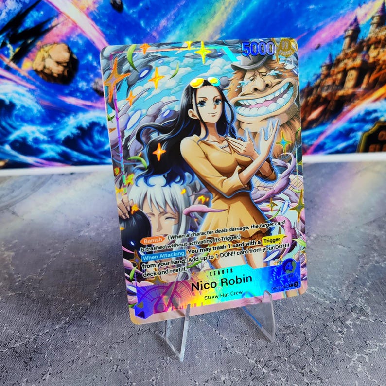 K&ouml;nnte beinhalten: Eine holografische One Piece Sammelkarte mit der Figur Nico Robin in einem beigen Outfit und langem dunklen Haar, vor einer gro&szlig;en l&auml;chelnden Kreatur. Die Karte zeigt den Text Leader Nico Robin, Straw Hat Crew sowie verschiedene Spielregeln.