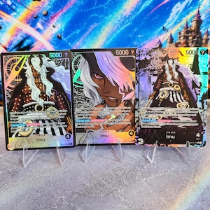 Op de afbeelding: Drie rechthoekige ruilkaarten met het personage Imu uit One Piece. Elke kaart toont een krachtniveau van 5000, een levenswaarde van 4 en tekst met spelregels. Het artwork toont een figuur met lang wit haar en een donkere huid.