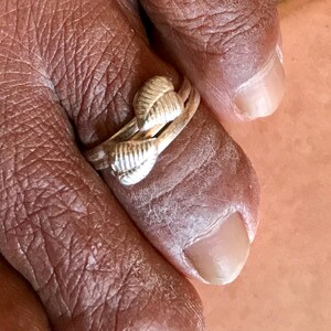 May include: A silver ring with a unique design featuring three textured, leaf-like elements. The ring is worn on a finger, showcasing its intricate details and craftsmanship. The ring's design is eye-catching and elegant.