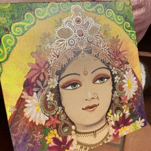 May include: A painting of a woman with a golden crown and floral decorations. The woman has dark hair, green eyes, and a gentle expression. The background is a vibrant green and yellow with swirling patterns.