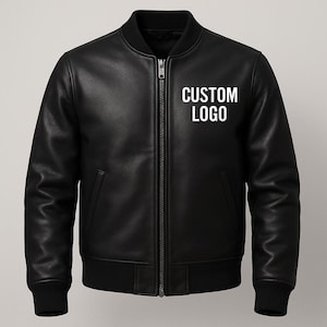 May include: A black leather bomber jacket with a zip fastening and ribbed cuffs and hem. The jacket features a classic design with a collar and two front pockets. The text "CUSTOM LOGO" is printed on the chest.