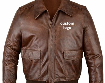 May include: A brown leather bomber jacket with a collar, two front pockets, and a ribbed hem. The jacket has a zipper closure and the text "custom logo" is visible on the chest.