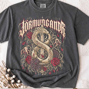 May include: A charcoal grey short-sleeve t-shirt featuring a graphic print of a coiled serpent wrapped around a sword. The text JORMUNGANDR is printed in a stylised font above the serpent, surrounded by red roses and dark floral elements.