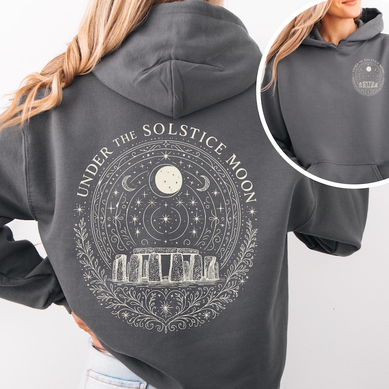 May include: Dark gray hoodie with a circular graphic on the back featuring Stonehenge, a moon, stars, and the text "UNDER THE SOLSTICE MOON." The front of the hoodie has a smaller matching graphic. The hoodie has a drawstring hood and a front pocket.