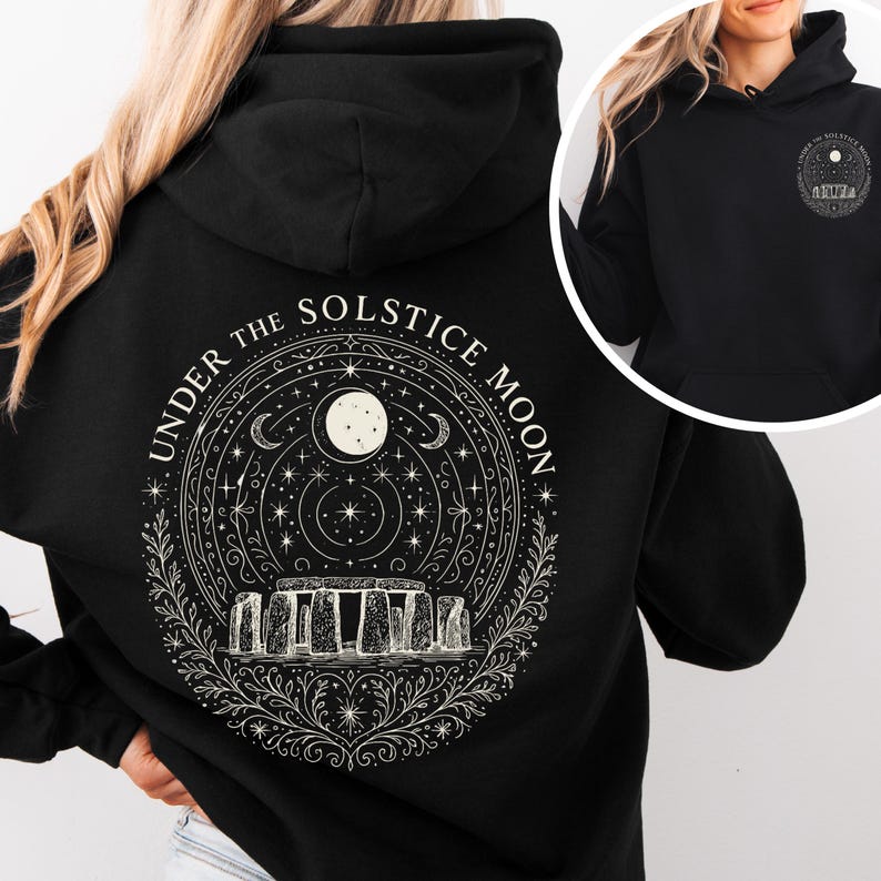 May include: Black hoodie featuring a circular design with the text "UNDER THE SOLSTICE MOON." The design includes a full moon, stars, crescent moons, and a depiction of Stonehenge. A smaller version of the design is on the front.