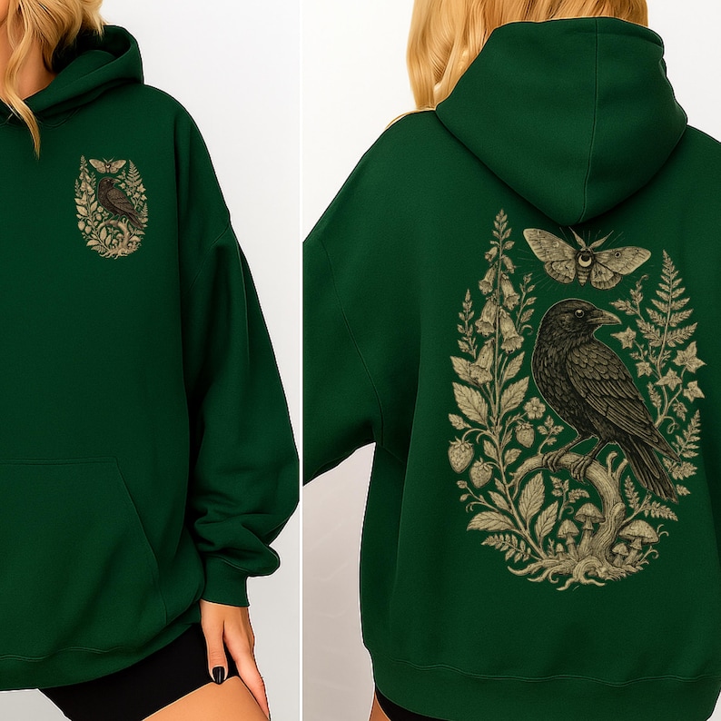 May include: A dark forest green hooded sweatshirt featuring a graphic print of a black crow perched on a branch, surrounded by botanical elements including a moth, ferns, mushrooms, and flowers, displayed on both the front and back.