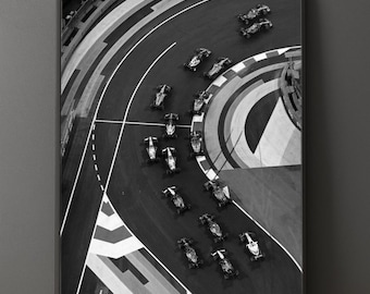 Puede incluir: Impresión enmarcada en blanco y negro de una carrera de Fórmula 1. La vista aérea muestra varios coches de carreras en una pista curva con marcas blancas. La imagen captura el movimiento dinámico de la carrera y el diseño de la pista.