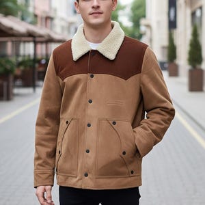 Puede incluir: Chaqueta de ante marrón claro con canesú marrón y cuello de borreguillo color crema. La chaqueta tiene botones negros, dos bolsillos delanteros y un estilo western clásico. Chaqueta de peso medio, adecuada para climas frescos.