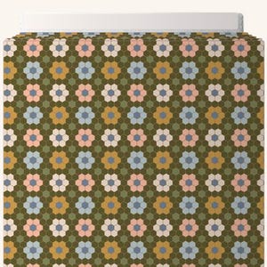 May include: A patterned fabric with a repeating floral design. The flowers are in shades of pink, blue, white, and gold, set against a dark green hexagonal background. The fabric is folded over a white surface.