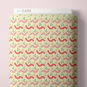 May include: A roll of fabric with a repeating pattern of pink and red caterpillars, blue flowers, and yellow accents on a cream background. The text "CLOUD9" is visible at the top. This fabric is suitable for sewing and crafting projects.