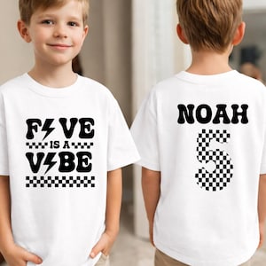 May include: White t-shirts with black text and graphics. One shirt says "FIVE is a VIBE" with a lightning bolt and checkered accents. The other shirt has the name "NOAH" and a checkered number "5".