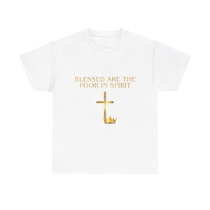 Puede incluir: Una camiseta blanca de manga corta con el texto dorado BLESSED ARE THE POOR IN SPIRIT centrado en el pecho. Debajo del texto hay un gráfico de una cruz dorada con una pequeña corona dorada colocada en la base de la cruz a la derecha.