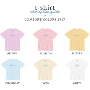 May include: A color guide for Comfort Colors 1717 t-shirts. The image displays six t-shirts in various colors: orchid, blossom, butter, chambray, ivory, and white. Each shirt has a small graphic and the color name below.