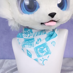 Pode incluir: Bandana branca e azul estampada com várias ilustrações, incluindo pegadas e sóis, exibida em uma cabeça de manequim branca. A bandana, feita de material macio, é projetada para ser usada ao redor do pescoço.