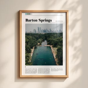 May include: A framed print featuring Barton Springs in Austin, Texas. The image shows a large, rectangular pool surrounded by trees, with a city skyline in the background. The text "Barton Springs" is at the top.