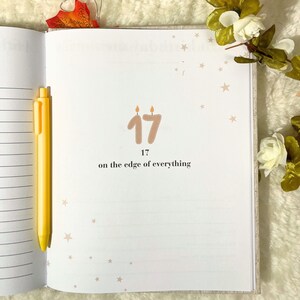 May include: An open journal with the number 17 and the text "on the edge of everything" printed on a page. A yellow pen rests on the left side. The page has small star illustrations.