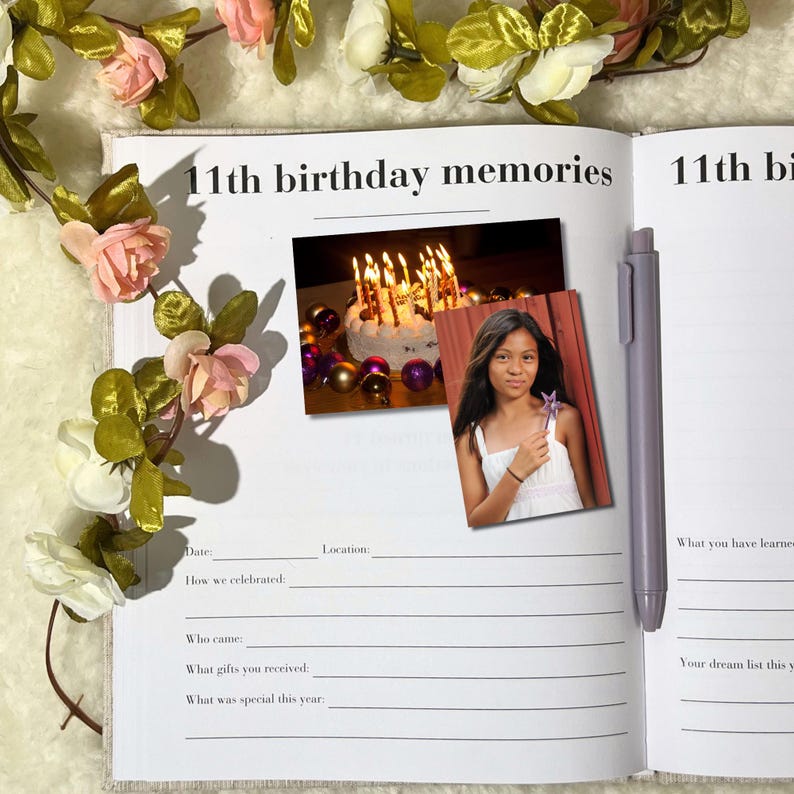 May include: An open memory book with the text "11th birthday memories." A photo of a girl holding a star wand and a birthday cake with lit candles are included. A pen rests on the right page, and floral accents frame the book.